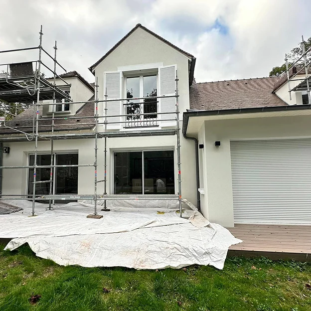 Maison en rénovation avec échafaudages, bâches au sol, murs blancs, toit marron et volets à Sartrouville dans les Yvelines 78