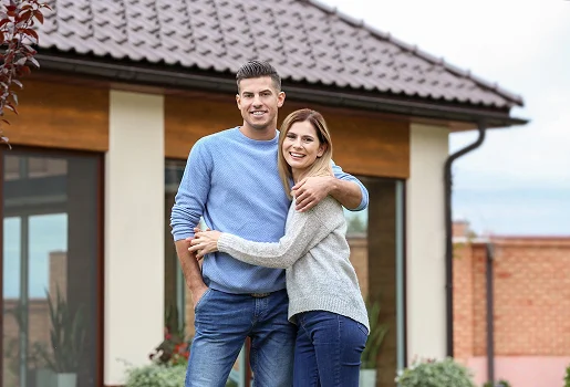 Couple souriant s'embrassant devant une maison avec un toit marron à Sartrouville dans les Yvelines 78